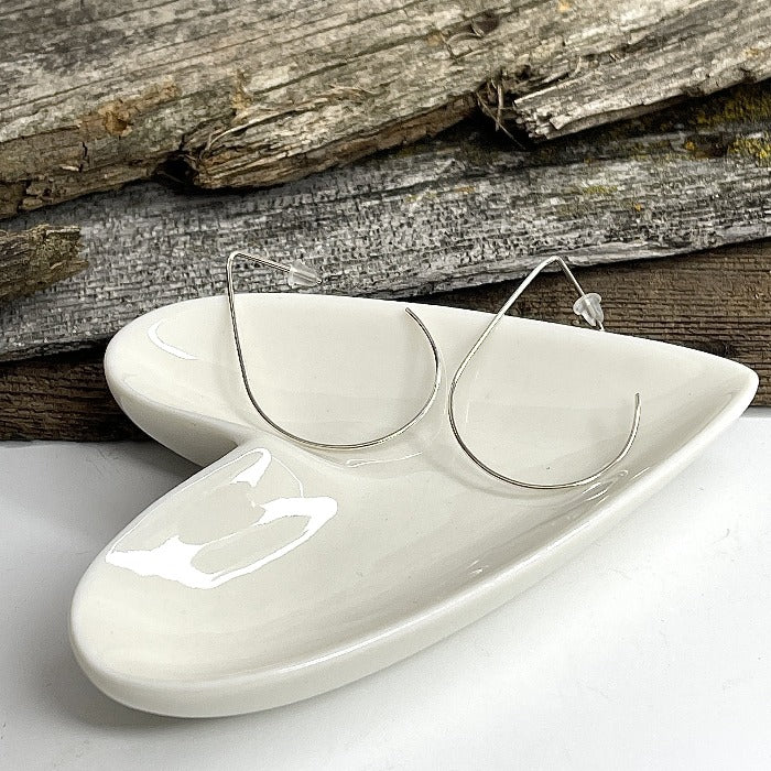 Teardrop shaped wire earrings in a heart shaped bowl.  Made of sterling silver. Minimal wire earrings.
