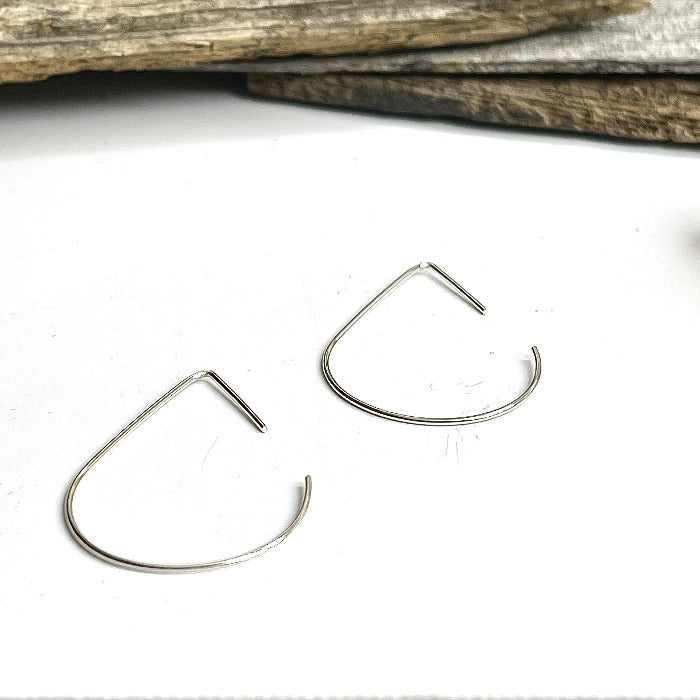 Teardrop shaped wire earrings in a heart shaped bowl.  Made of sterling silver. Minimal wire earrings.