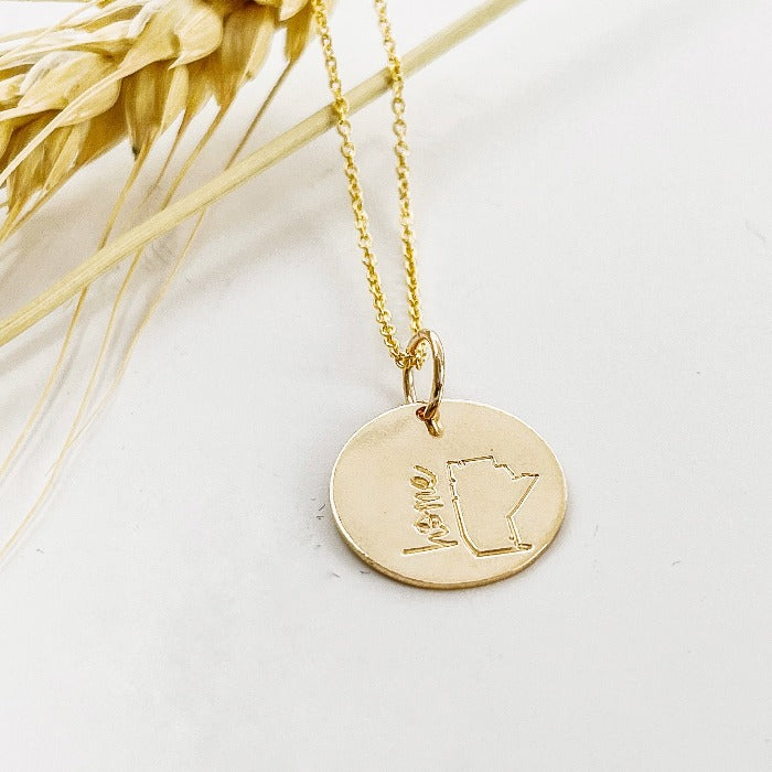 Gold Filled Mini Manitoba necklace laying on a stem of wheat